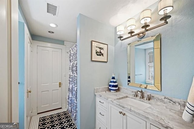 full bath featuring curtained shower, visible vents, and vanity