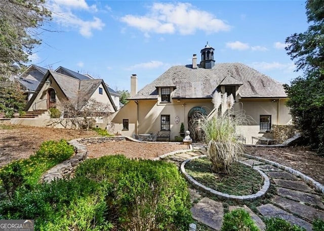 back of house with a chimney and stucco siding