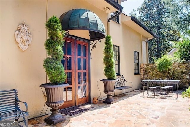 property entrance with a patio, french doors, outdoor dining space, and stucco siding