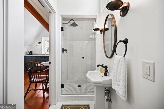 bathroom with lofted ceiling, a shower stall, and wood finished floors