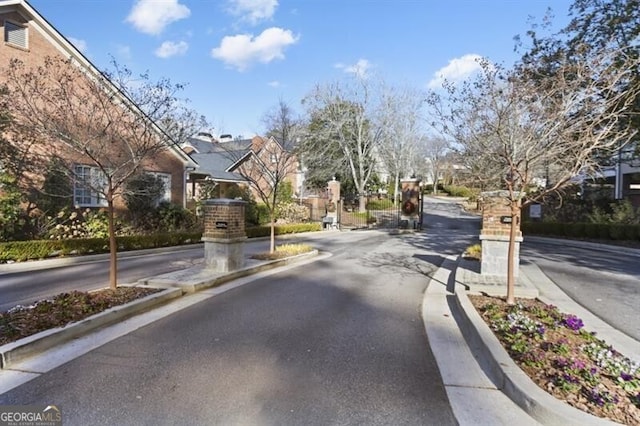 view of road with a residential view, curbs, and a gated entry