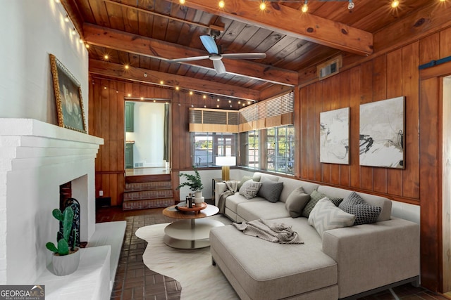 living area with beam ceiling, ceiling fan, wooden ceiling, and wood walls