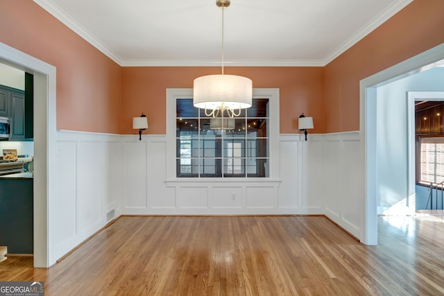 unfurnished dining area with ornamental molding and light wood-type flooring