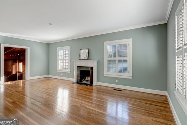 unfurnished living room featuring light hardwood / wood-style floors, a premium fireplace, ornamental molding, and a wealth of natural light