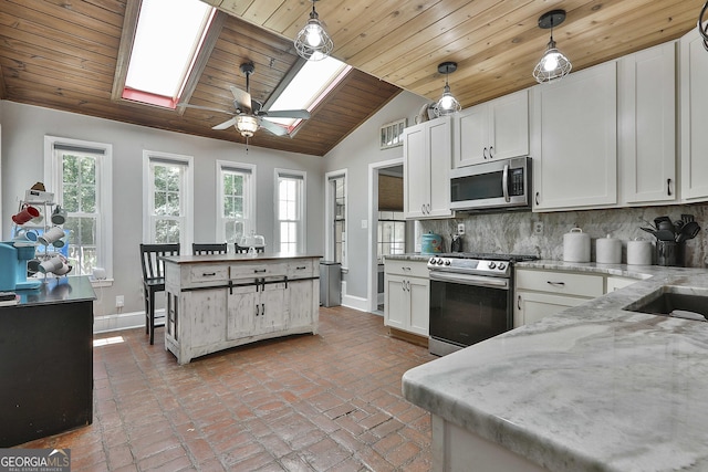 kitchen featuring stainless steel appliances, white cabinetry, and decorative light fixtures