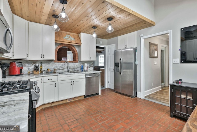 kitchen featuring white cabinets, stainless steel appliances, hanging light fixtures, sink, and backsplash