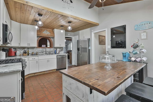 kitchen with stainless steel appliances, decorative light fixtures, white cabinets, backsplash, and wood ceiling