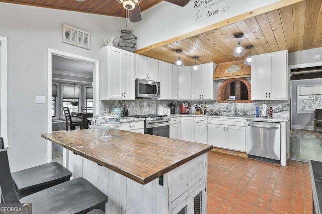 kitchen with stainless steel appliances, decorative light fixtures, white cabinetry, ceiling fan, and tasteful backsplash