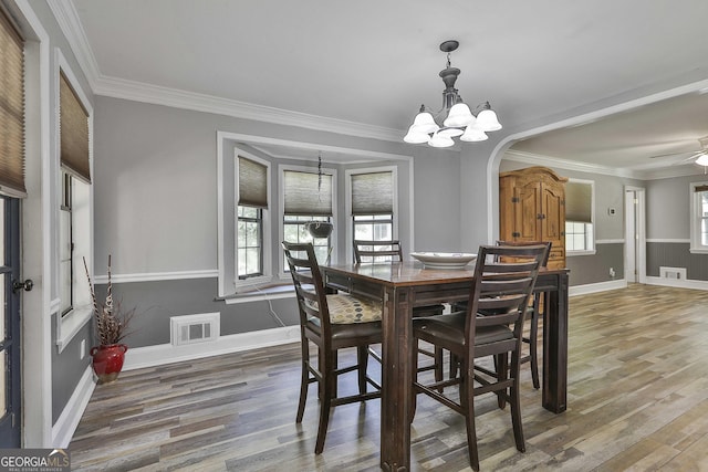 dining space featuring ornamental molding, hardwood / wood-style floors, and ceiling fan with notable chandelier