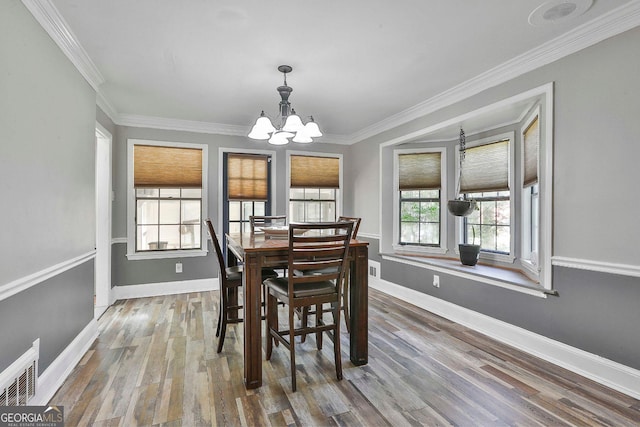 dining area featuring a notable chandelier, hardwood / wood-style floors, and crown molding