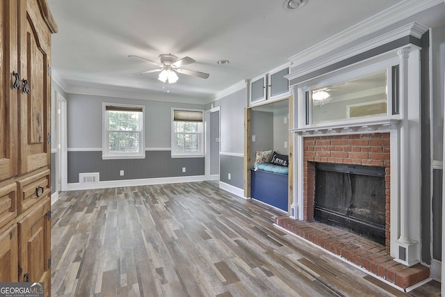 unfurnished living room featuring ceiling fan, a fireplace, ornamental molding, and hardwood / wood-style flooring