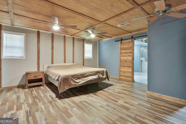 bedroom with ceiling fan, wood ceiling, light hardwood / wood-style floors, and a barn door