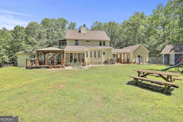 rear view of house featuring a sunroom and a lawn