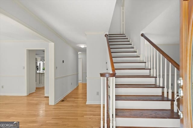 stairs with ornamental molding and wood-type flooring