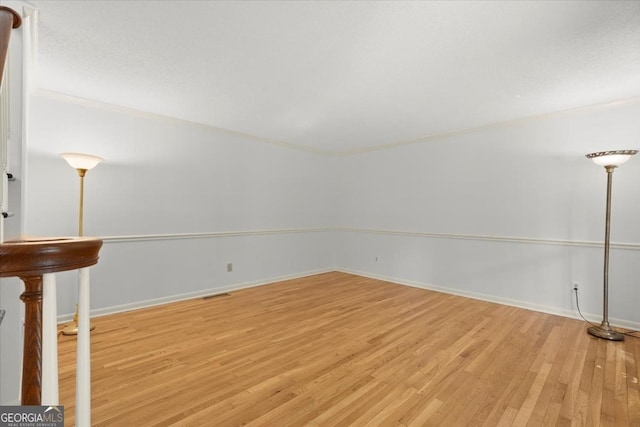 spare room featuring crown molding and light wood-type flooring