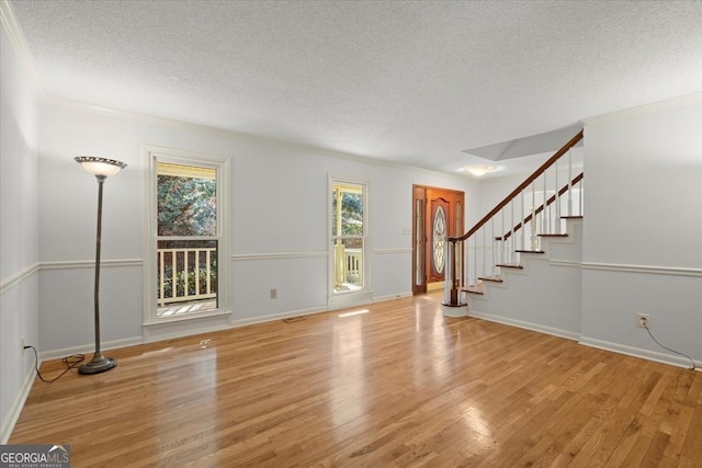 unfurnished living room with light wood-type flooring and a textured ceiling