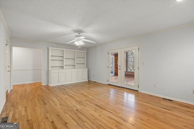 interior space featuring french doors, ornamental molding, a textured ceiling, and light wood-type flooring