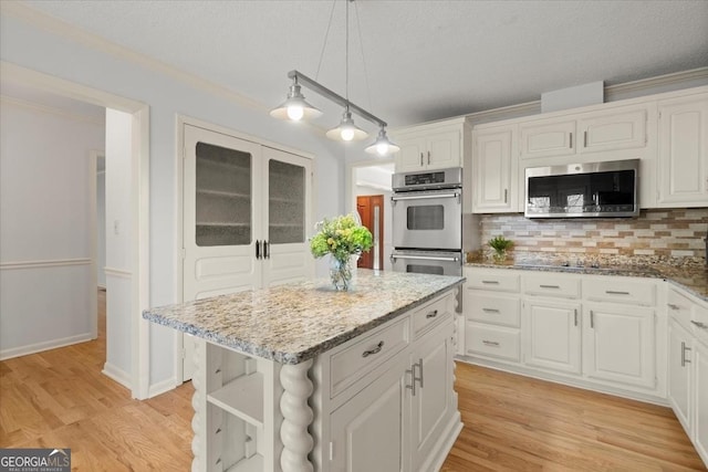 kitchen featuring hanging light fixtures, backsplash, white cabinetry, a kitchen island, and stainless steel appliances