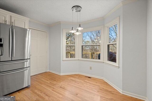 interior space with light wood-type flooring, crown molding, and a textured ceiling