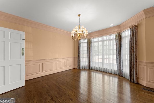 spare room with crown molding, dark hardwood / wood-style floors, and a chandelier