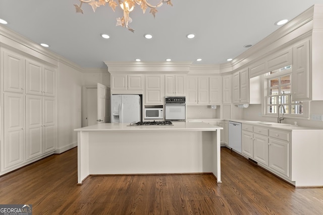 kitchen featuring sink, white cabinetry, ornamental molding, a kitchen island, and white appliances