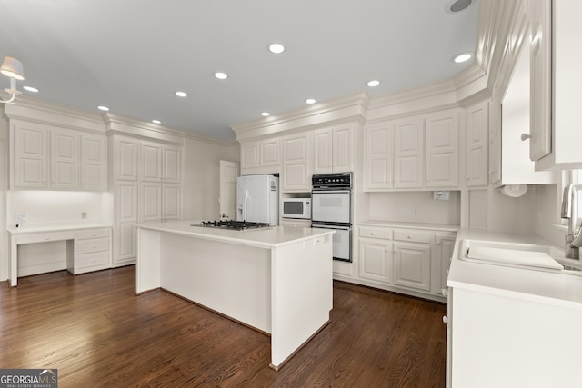 kitchen with sink, dark hardwood / wood-style floors, a kitchen island, white appliances, and white cabinets