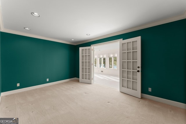 spare room featuring light carpet, crown molding, and french doors