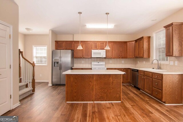 kitchen featuring pendant lighting, stainless steel appliances, a kitchen island, dark hardwood / wood-style flooring, and sink