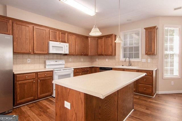 kitchen featuring stainless steel appliances, dark hardwood / wood-style floors, a kitchen island, sink, and decorative light fixtures