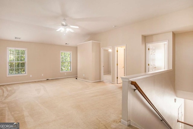 spare room featuring a healthy amount of sunlight, ceiling fan, and light carpet