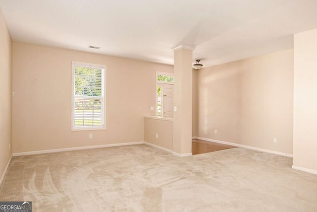 carpeted spare room featuring ornate columns