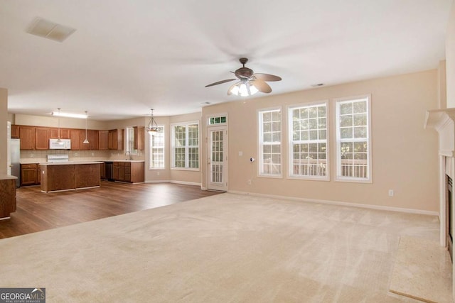 unfurnished living room with sink, a premium fireplace, ceiling fan, and carpet