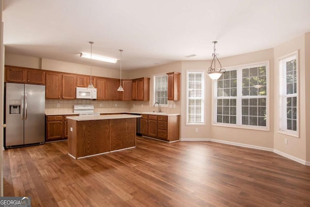 kitchen featuring pendant lighting, a center island, range, stainless steel fridge with ice dispenser, and dark hardwood / wood-style flooring