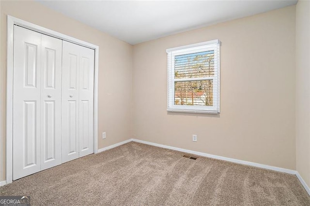 unfurnished bedroom featuring a closet and light carpet