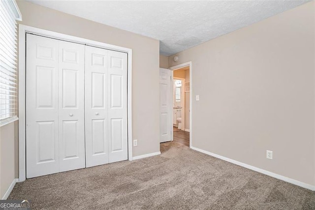 unfurnished bedroom with a textured ceiling, multiple windows, a closet, and carpet floors