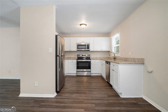 kitchen featuring stainless steel appliances, light stone countertops, dark hardwood / wood-style floors, sink, and white cabinetry