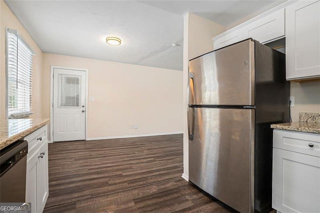 kitchen with white cabinets, dark hardwood / wood-style floors, light stone counters, and appliances with stainless steel finishes