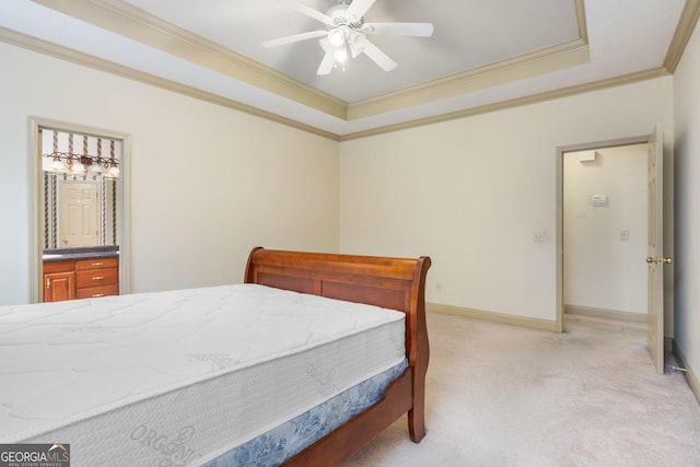 bedroom with baseboards, ornamental molding, light carpet, a raised ceiling, and ensuite bath