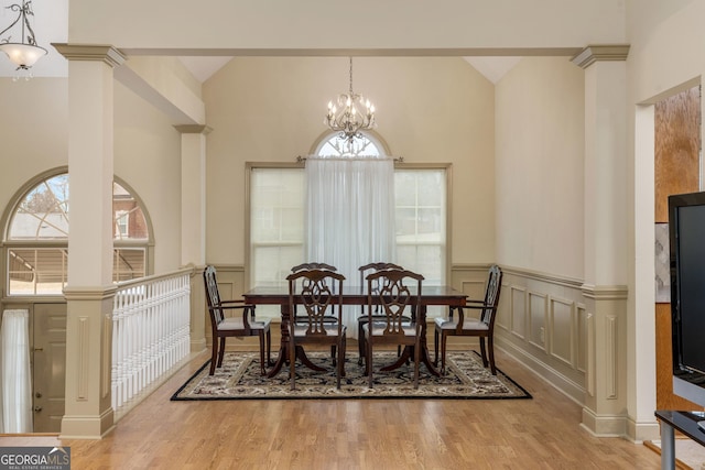 dining room with a wealth of natural light, a notable chandelier, wood finished floors, and a decorative wall