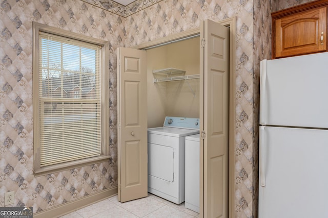 laundry area with light tile patterned floors, baseboards, wallpapered walls, washing machine and clothes dryer, and laundry area