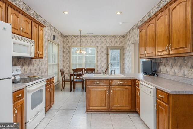 kitchen with sink, white appliances, kitchen peninsula, a chandelier, and pendant lighting