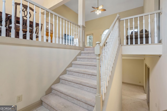 stairs featuring carpet floors, baseboards, and ceiling fan