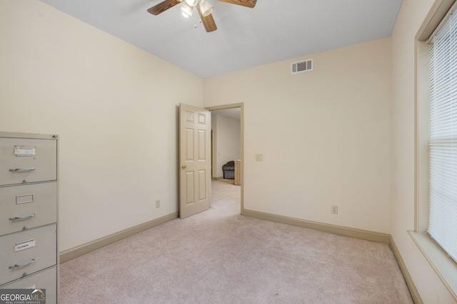 spare room featuring light carpet, baseboards, ceiling fan, and visible vents