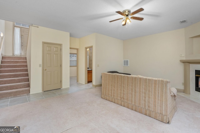 living room with a fireplace with flush hearth, visible vents, carpet, stairs, and a ceiling fan