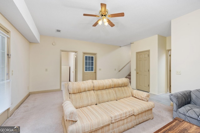 living room with visible vents, baseboards, stairs, a ceiling fan, and light carpet
