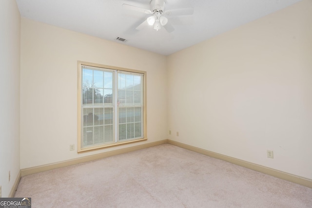 spare room featuring carpet floors, baseboards, ceiling fan, and visible vents