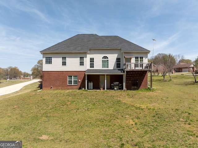back of house with a lawn, brick siding, a wooden deck, and roof with shingles