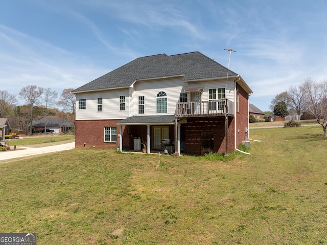 back of property featuring a shingled roof, a wooden deck, brick siding, and a yard