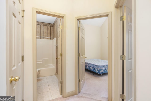 hall with light carpet and light tile patterned floors