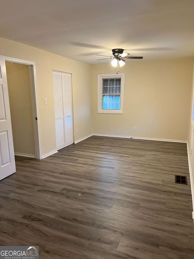 unfurnished bedroom featuring ceiling fan and dark hardwood / wood-style flooring